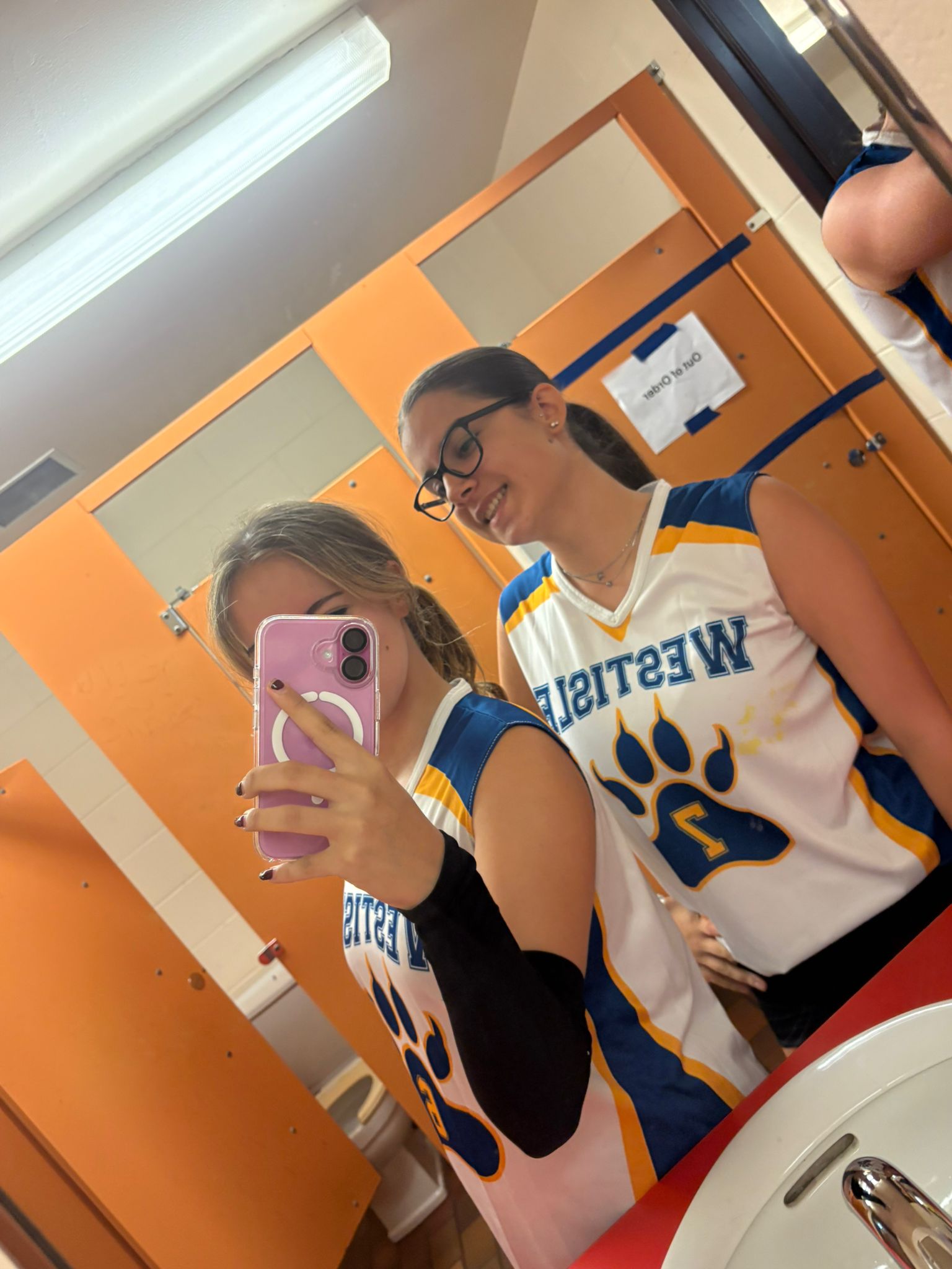 Two people in matching Westisle sports jerseys take a mirror photo